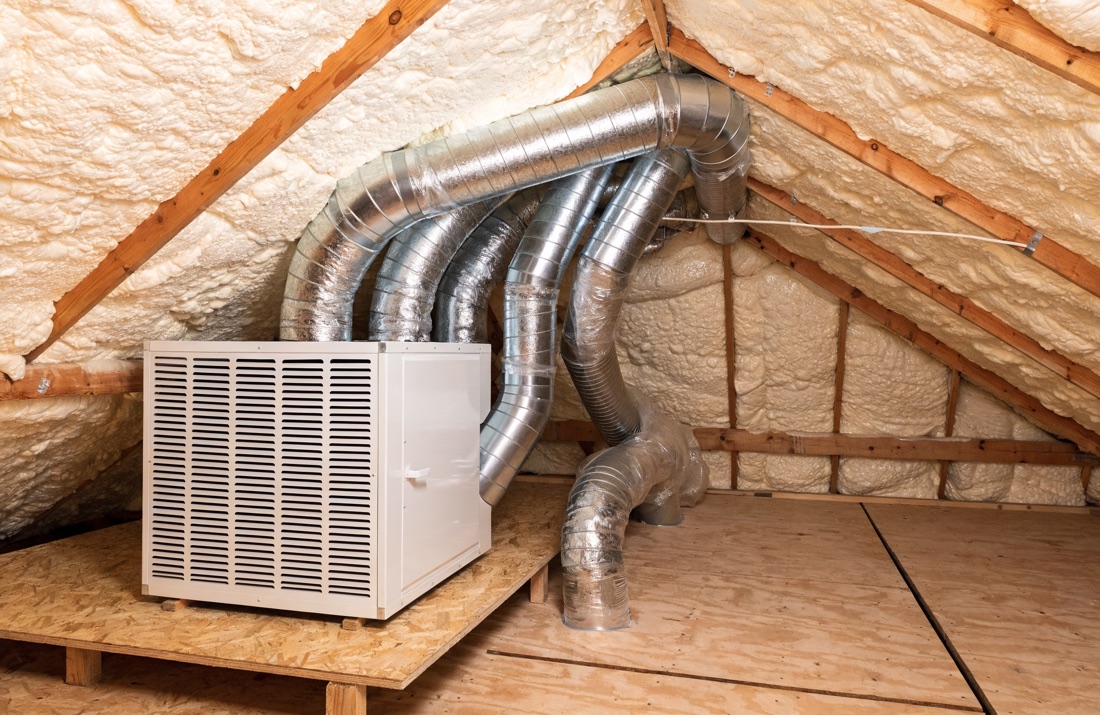 Flexible HVAC duct runs and an air handler inside an attic with a foam-insulated roof deck above them